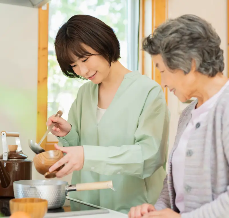 窓辺で介護スタッフと穏やかに過ごす高齢の女性